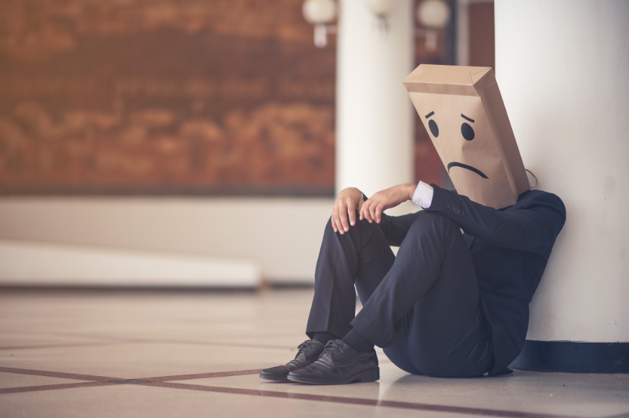 male in business suit wearing brown bag with sad face