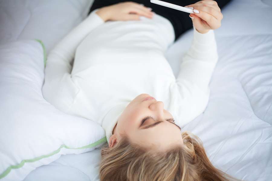 woman in white holding pregnancy test thinking of her fertility journey
